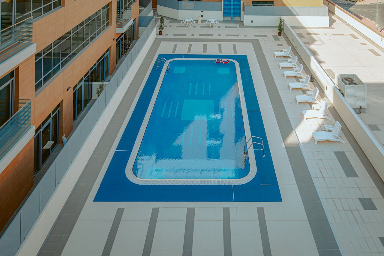 High-angle view of a modern apartment complex rooftop pool with sunloungers.